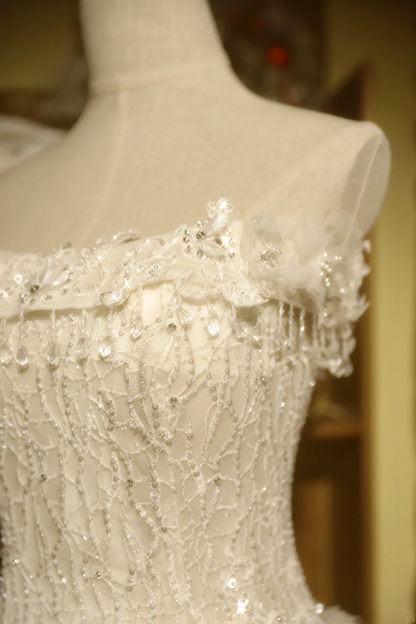 White strapless ball gown with a cinched waist and a voluminous tiered cake skirt; bridal gown R7289